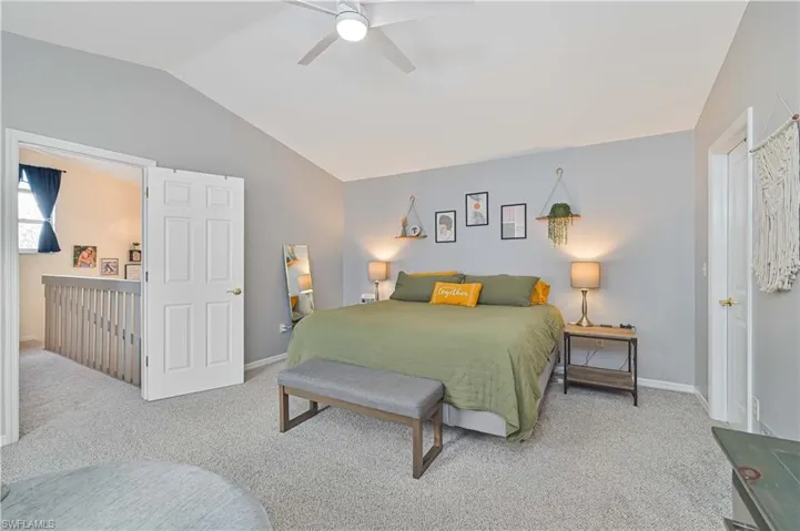 Bedroom featuring light colored carpet, lofted ceiling, and a ceiling fan