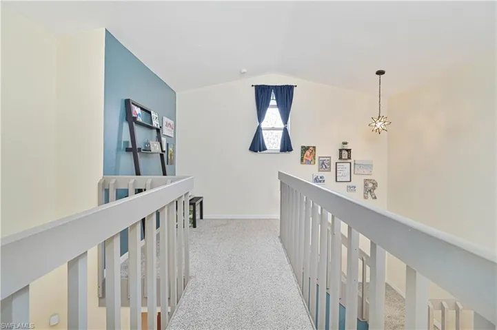 Corridor featuring light colored carpet, lofted ceiling, and an upstairs landing
