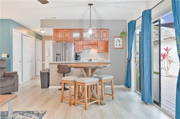 Kitchen with light countertops, tasteful backsplash, stainless steel fridge, glass fronted cabinets, and light wood-style flooring