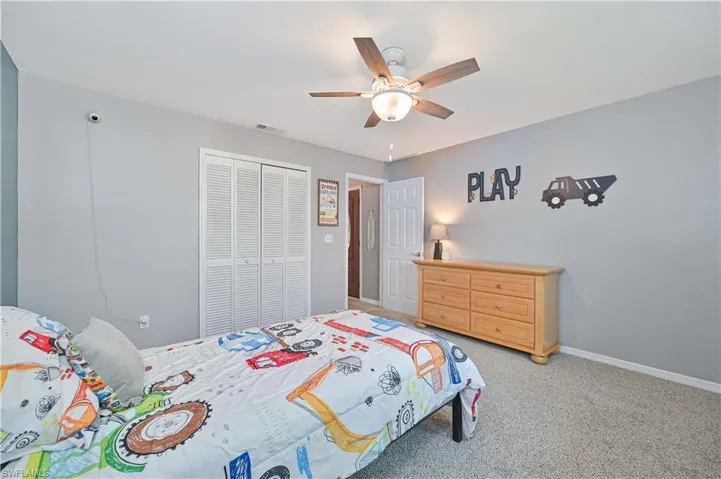 Bedroom with light colored carpet, a closet, and ceiling fan