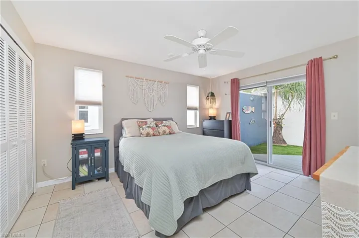Bedroom with light tile patterned flooring, access to outside, multiple windows, and a closet