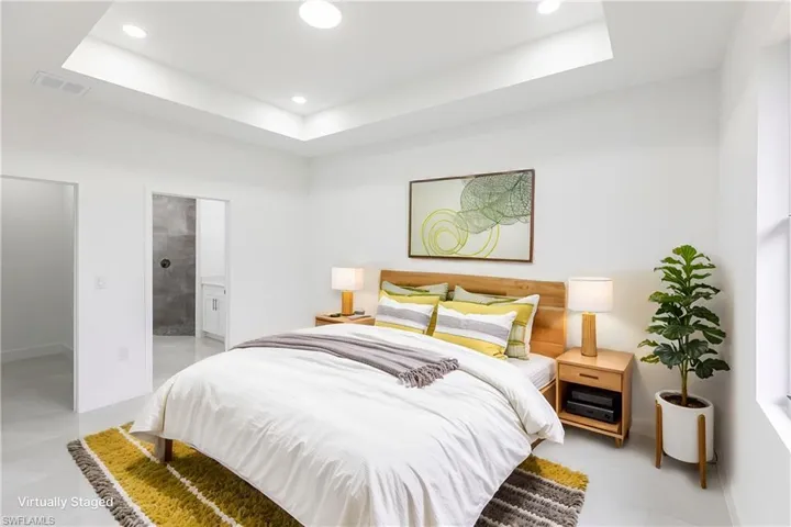 Bedroom featuring a raised ceiling and ensuite bath