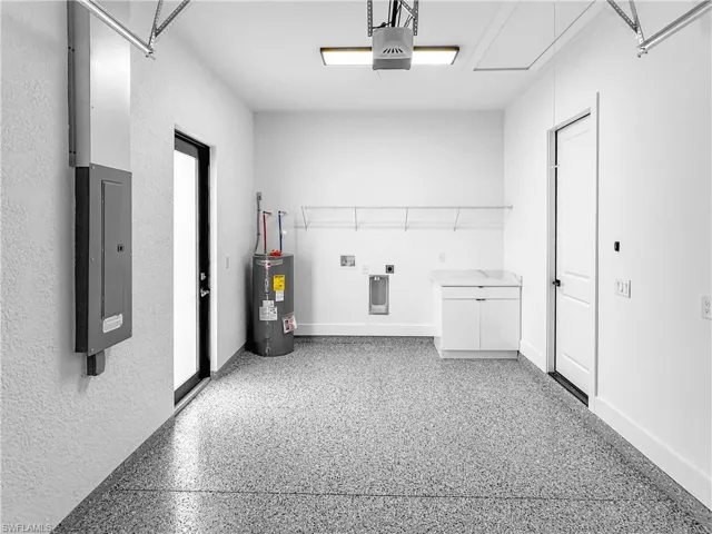 Laundry room featuring a garage, electric dryer hookup, and electric panel