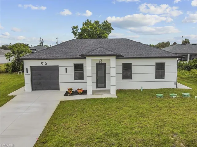 View of front of property with driveway, a front yard, and a garage
