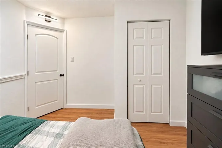 Wood-finish flooring, white paneled door, and bi-fold closet doors