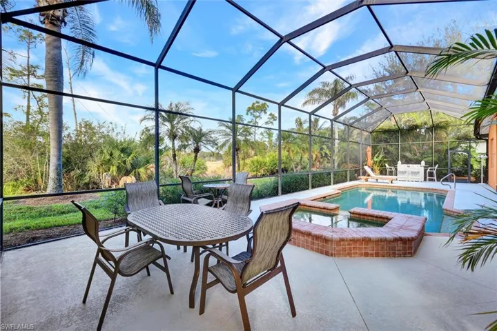 View of patio featuring glass enclosure and a pool with hot tub