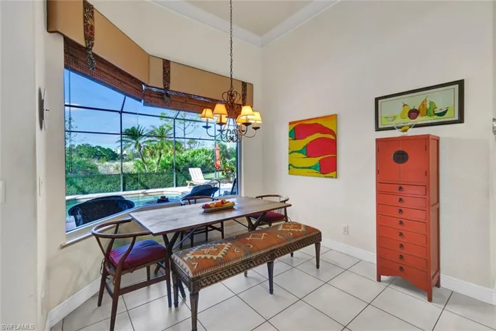 Dining area with tile patterned flooring, crown molding, and a chandelier