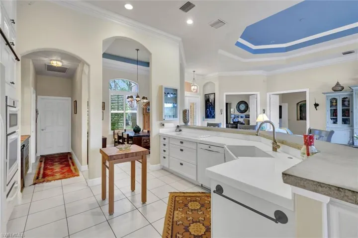 Kitchen with white cabinets, pendant lighting, white appliances, and sink