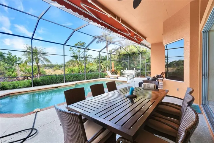 View of swimming pool with glass enclosure, ceiling fan, and a patio