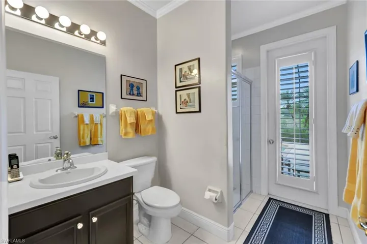 Bathroom featuring toilet, vanity, tile patterned floors, and an enclosed shower