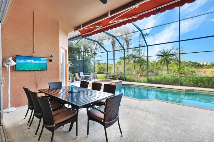 View of swimming pool with glass enclosure and a patio