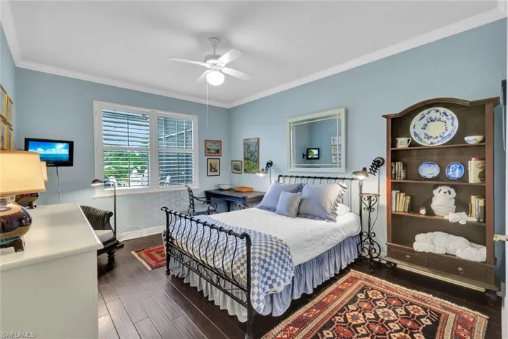 Bedroom featuring ceiling fan, crown molding, and dark wood-type flooring