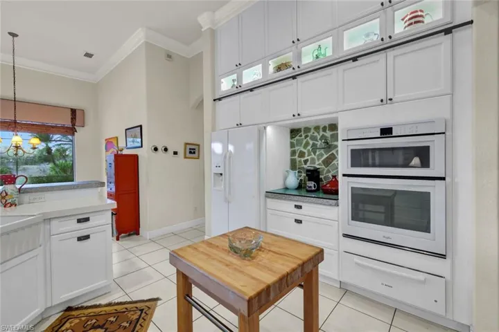 Kitchen featuring white appliances, white cabinetry, hanging light fixtures, and a healthy amount of sunlight