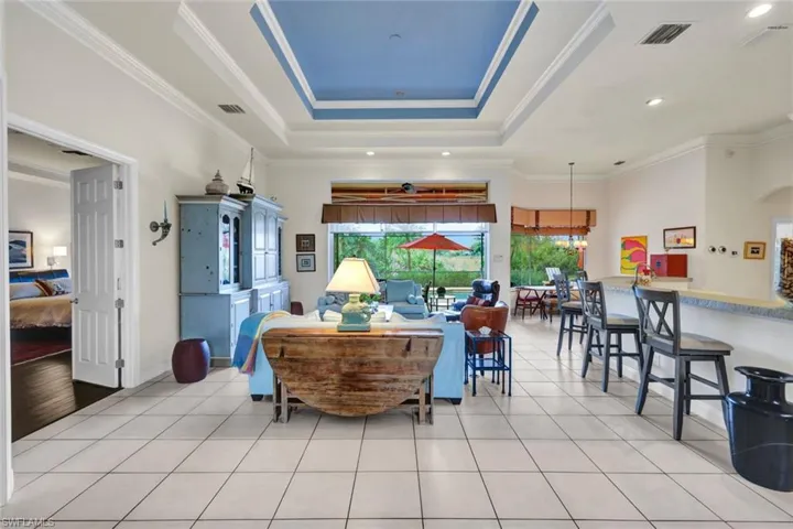 Living room featuring a raised ceiling, light hardwood / wood-style floors, and ornamental molding