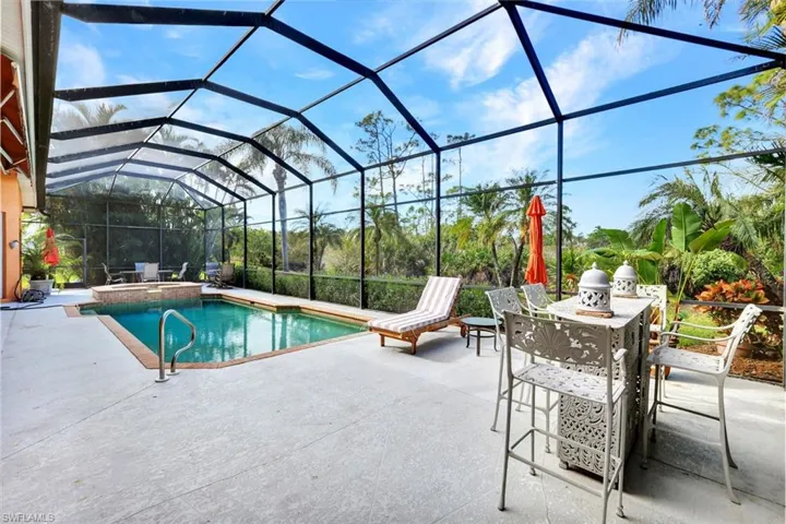 View of swimming pool with glass enclosure and a patio