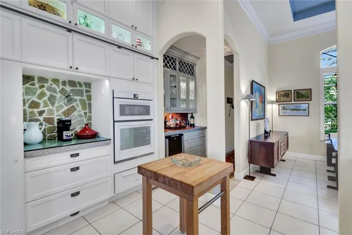 Kitchen with ornamental molding, white cabinetry, and a healthy amount of sunlight