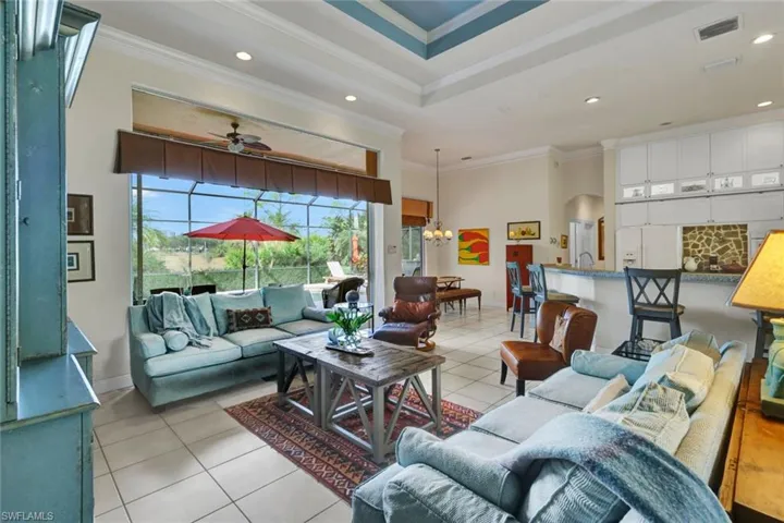 Tiled living room with ceiling fan with notable chandelier and ornamental molding