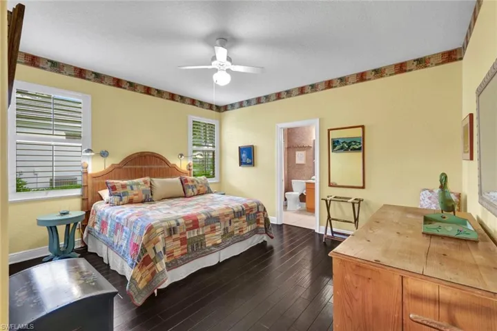 Bedroom with ceiling fan, dark hardwood / wood-style floors, and ensuite bath