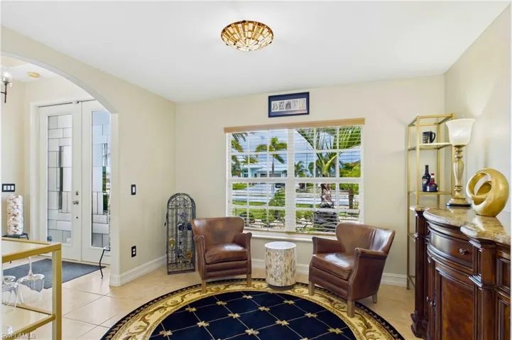 Front room with large window featuring natural light, tile flooring, an arched entryway, and a decorative ceiling light fixture