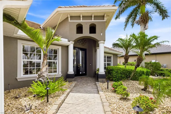 Modern Mediterranean-style facade featuring a prominent arched entryway with double glass doors
