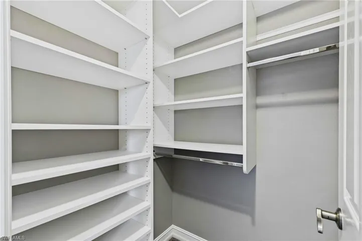 Custom white shelving system featuring adjustable shelves and multiple hanging rods