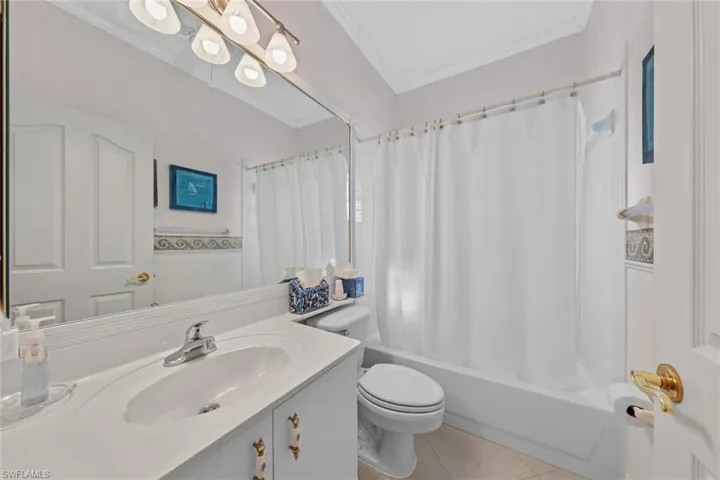 Full bathroom featuring vanity, crown molding, tile patterned flooring, toilet, and shower / bath combo with shower curtain