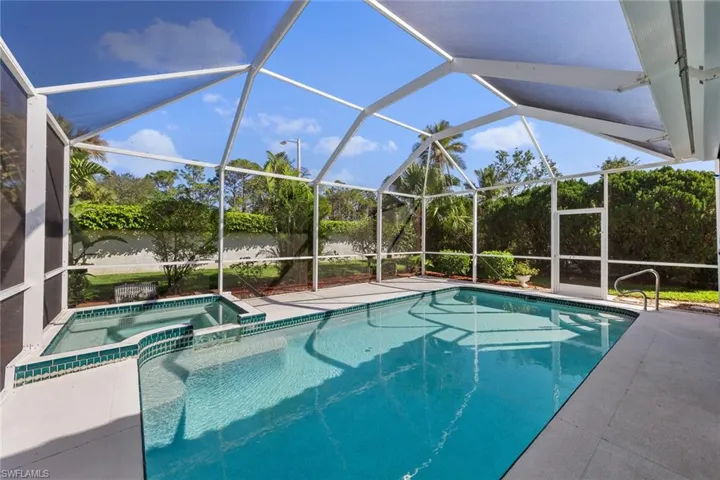 View of pool featuring glass enclosure, an in ground hot tub, and a patio