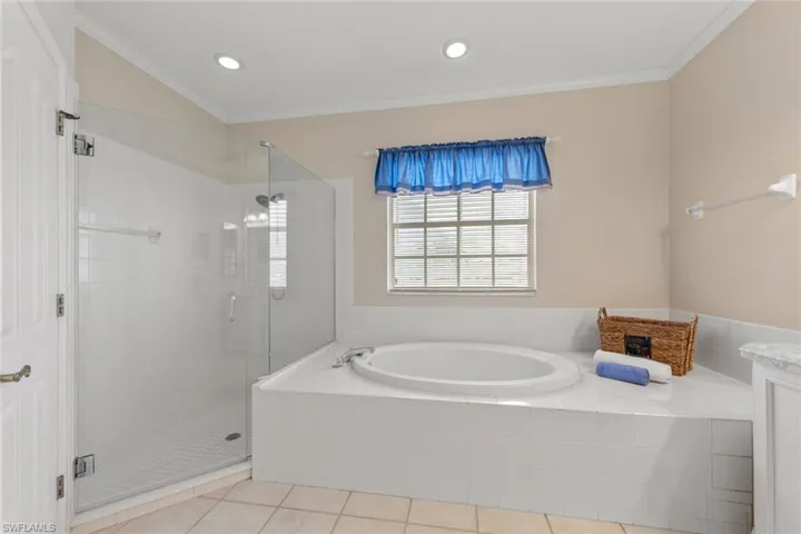 Bathroom featuring tile patterned flooring, vaulted ceiling, shower with separate bathtub, vanity, and ornamental molding