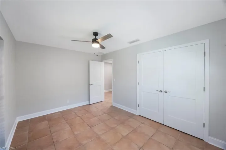 Unfurnished bedroom featuring visible vents, ceiling fan, baseboards, light tile patterned floors, and a closet