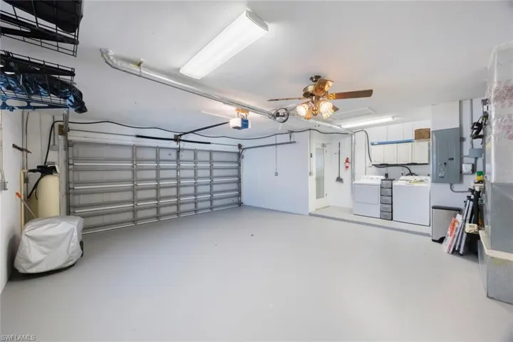 Garage featuring washer and dryer, electric panel, a garage door opener, and ceiling fan