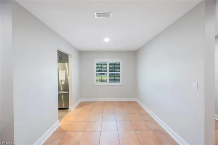 Empty room featuring light tile patterned flooring, visible vents, and baseboards