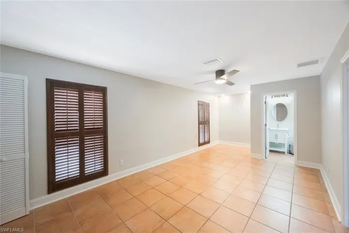 Spare room featuring light tile patterned floors, visible vents, baseboards, and a ceiling fan