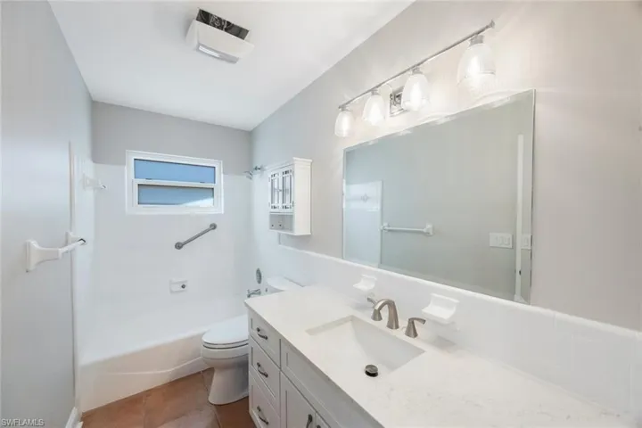 Bathroom featuring tile patterned floors, toilet, shower / washtub combination, and vanity