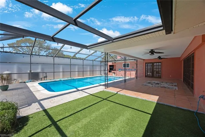 Outdoor pool featuring a patio area, glass enclosure, french doors, and ceiling fan