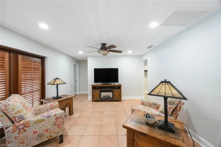 Living room with light tile patterned floors, a ceiling fan, visible vents, baseboards, and recessed lighting