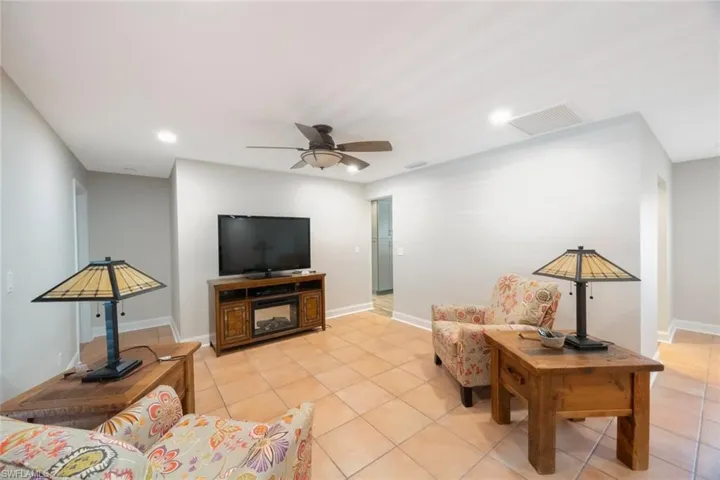 Living room featuring light tile patterned floors, visible vents, baseboards, and ceiling fan