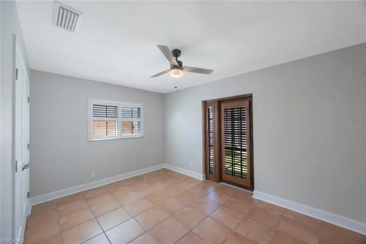 Unfurnished room with light tile patterned floors, visible vents, ceiling fan, and baseboards