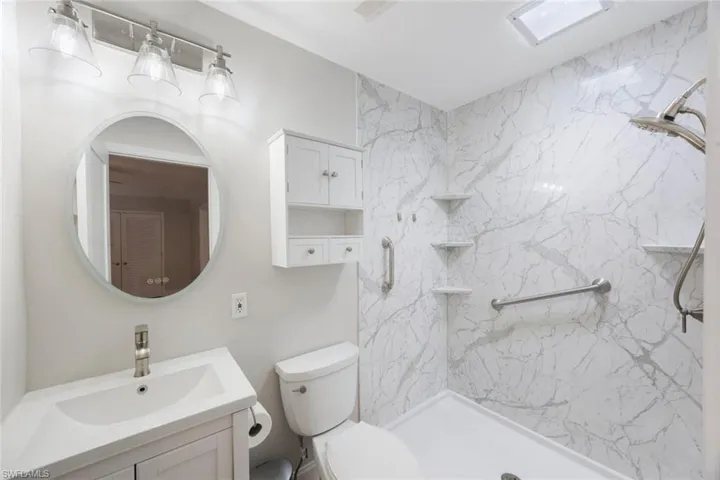 Full bathroom with a marble finish shower, toilet, and vanity