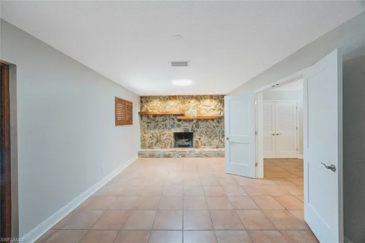 Unfurnished living room with visible vents, baseboards, light tile patterned floors, a fireplace, and a textured ceiling