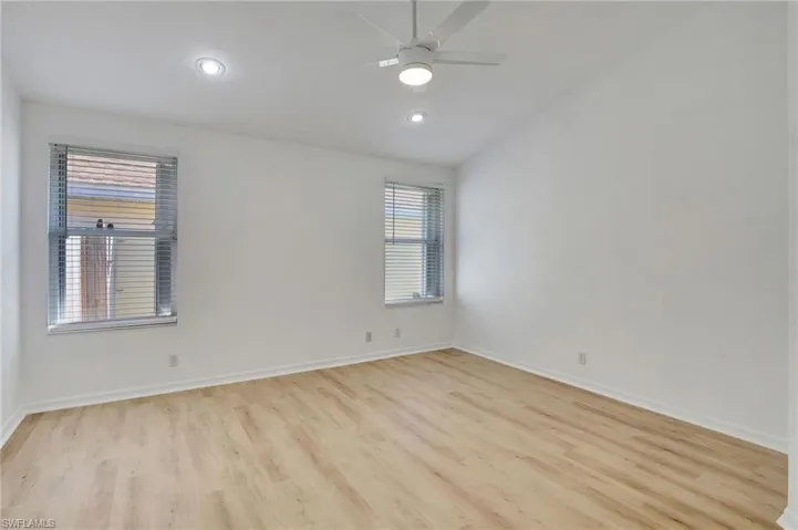 Spare room featuring ceiling fan, vaulted ceiling, and light wood-type flooring