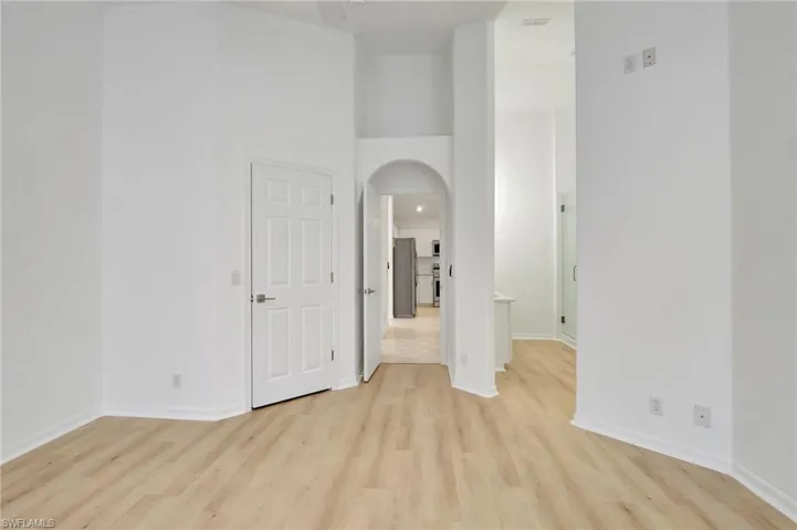 Empty room with a high ceiling and light hardwood / wood-style floors