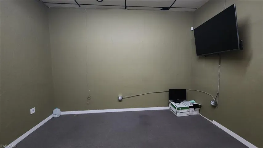 Carpeted empty room featuring a drop ceiling and baseboards