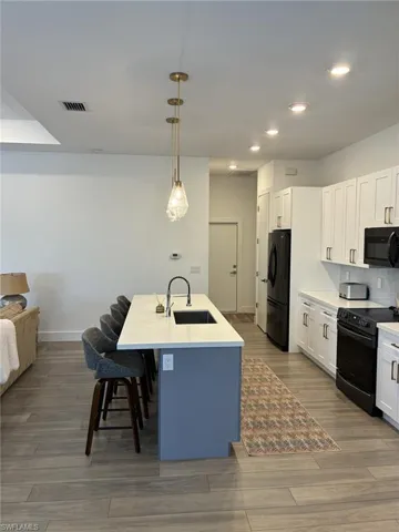 Kitchen island with a light-colored countertop and a built-in sink, featuring a matte black faucet