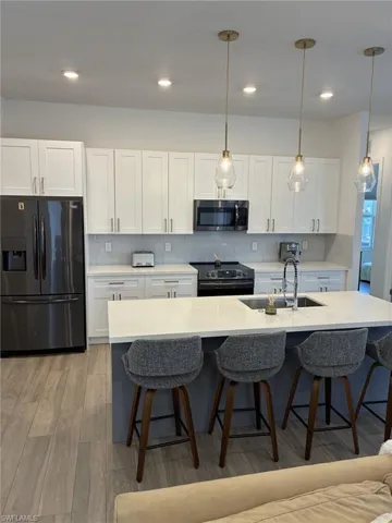 Modern kitchen featuring a large central island with seating, white shaker-style cabinetry, and a subway tile backsplash