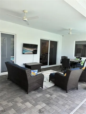 Covered patio featuring paver flooring, white ceiling fans, and sliding glass doors