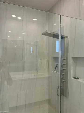 Sleek glass shower enclosure featuring a multi-function shower panel with rain shower head