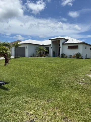 Contemporary stucco exterior with a prominent entry portico, a white tile roof, and a large front lawn