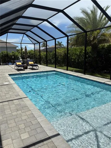 Screened outdoor swimming pool with paver decking and integrated steps