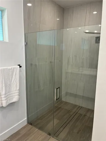 Glass-enclosed shower featuring a linear drain and wood-finish tile flooring
