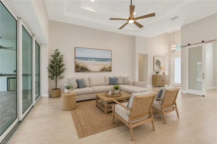 Living room with trey ceiling overlooking the lanai and pool through pocketing sliding glass doors